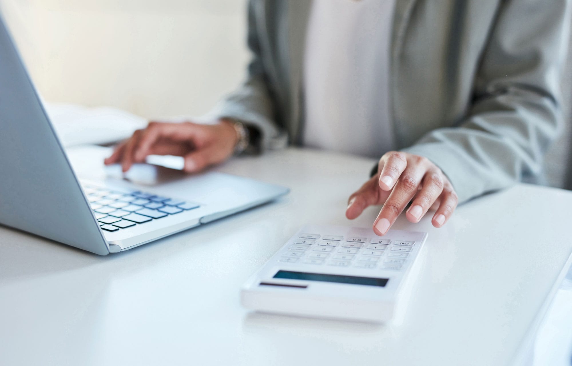 Woman using a calculator and laptop