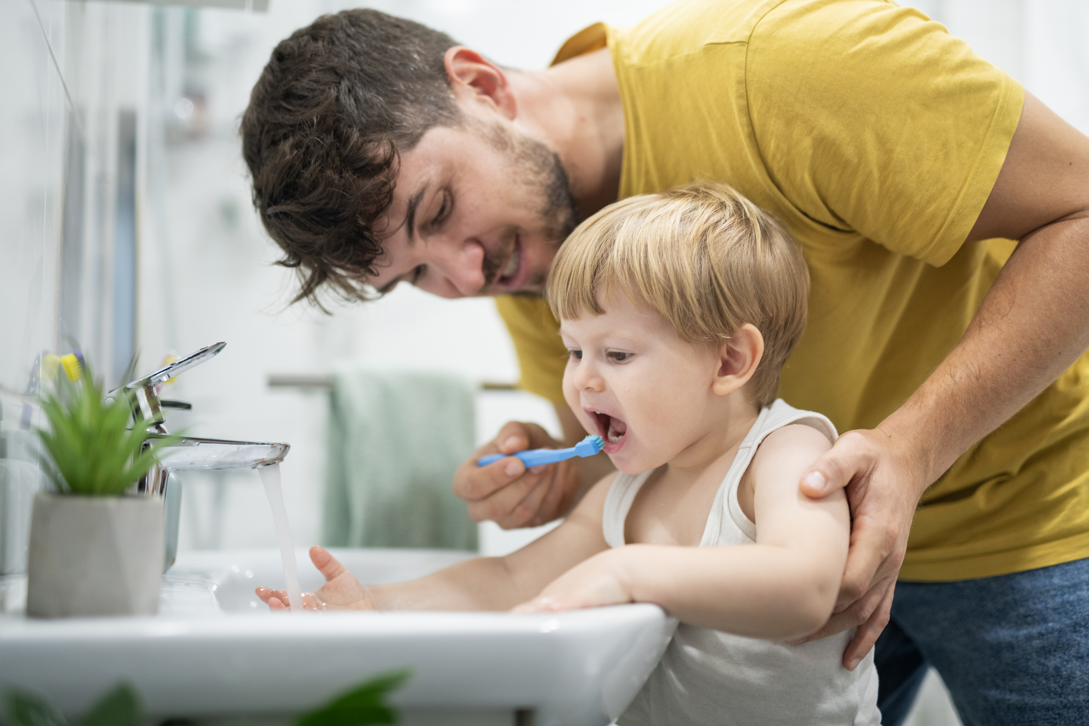 Boy enjoying washing his teeth with dad